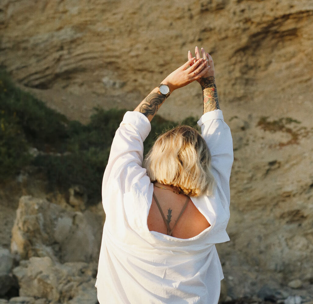 A woman with tattoos stretches and practices deep breathing techniques for anxiety in Dallas